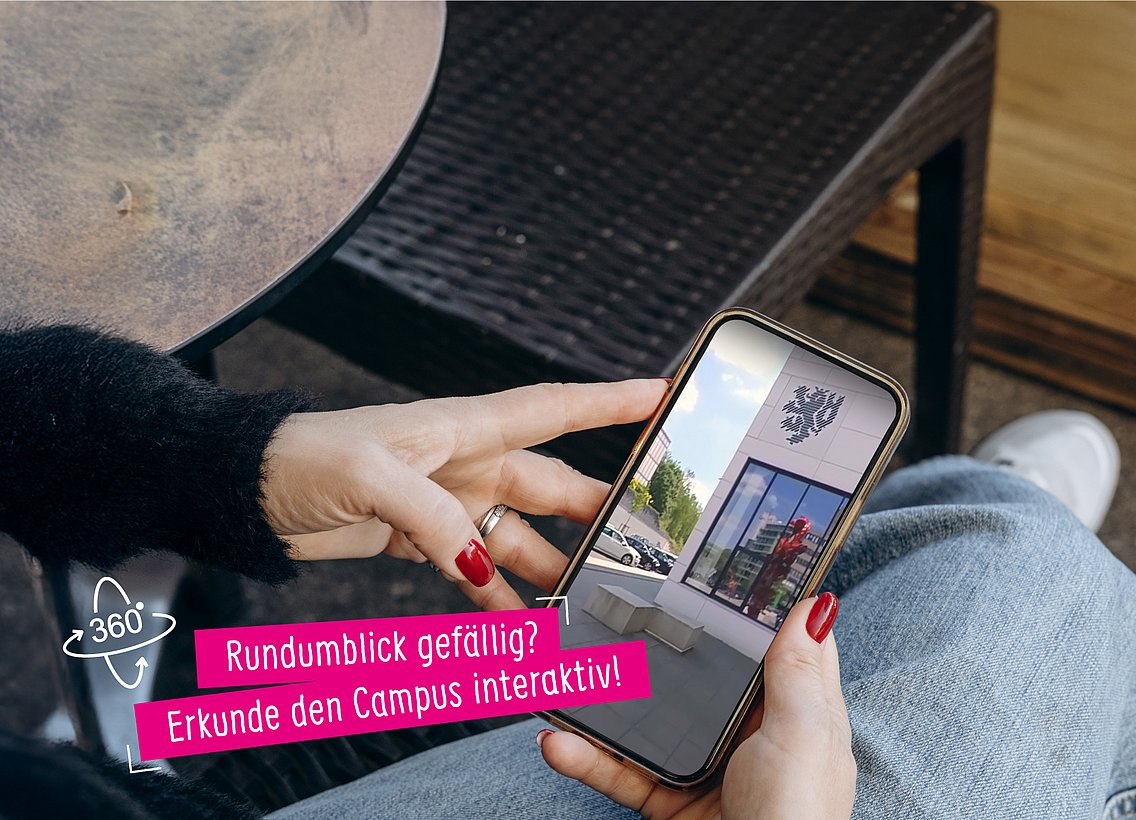 Im Schoß einer Person liegt ein Smartphone. Die Finger der Person halten das Smartphone fest. Auf dem Display des Handys sieht man den Campus der Uni  Wuppertal